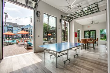 Houston apartment for rent - a ping pong table in the center of a living room with a large patio