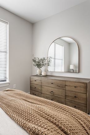 Westfield apartment for rent - A bedroom with a bed covered in a tan blanket, a wooden dresser, and a mirror above it.