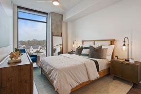 Nashville apartment for rent - A bedroom with a large bed and a view of houses through a window.