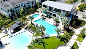 Plantation apartment for rent - A large swimming pool surrounded by a grassy area and a building in the background.