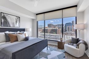 Denver apartment for rent - A bedroom with a large bed and a view of the city.