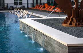 Carrollton apartment for rent - A pool with a waterfall feature and orange lounge chairs.