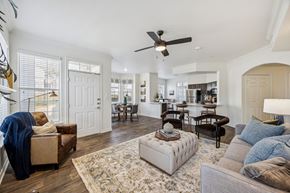 Plano apartment for rent - A living room with a rug, a couch, a chair, a table, and a ceiling fan.