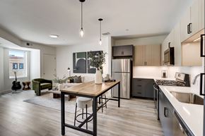 Des Plaines apartment for rent - A modern kitchen with a wooden table and stools, a refrigerator, and a sink.