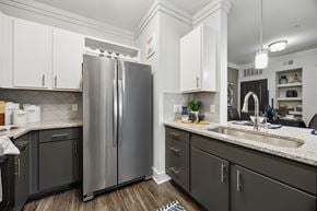 Fort Worth apartment for rent - A modern kitchen with a stainless steel refrigerator and dark grey cabinets.
