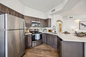 Plano apartment for rent - A modern kitchen with a stainless steel refrigerator and wooden cabinets.