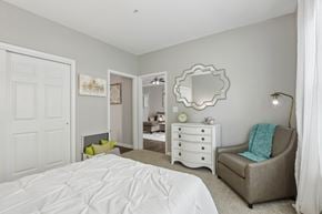 Mt Laurel apartment for rent - A bedroom with a white bed and a grey chair.