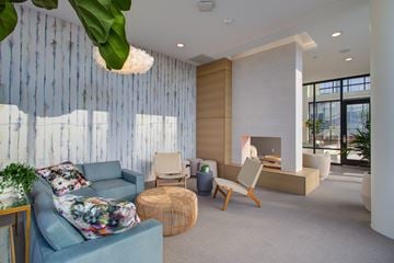 Minneapolis apartment for rent - A living room with a blue couch and a woven ottoman.