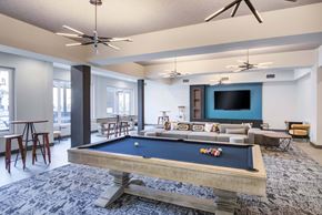 Norwalk apartment for rent - The Beacon game room lounge with billiards table, shuffleboard, arcade table, couches, high top tables, and a wall mounted tv