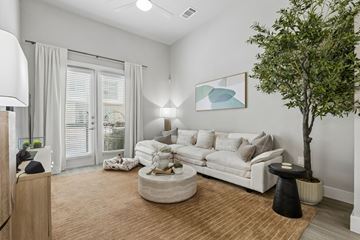 Richardson apartment for rent - A living room with a white couch, a tree, and a painting on the wall.