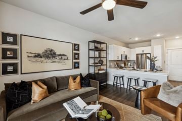 Prosper apartment for rent - A living room with a grey couch and a coffee table with a book and fruit on it.
