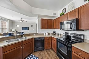 Fort Worth apartment for rent - A kitchen with black appliances and wooden cabinets.
