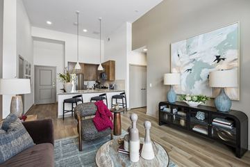 Plano apartment for rent - A modern living room with a grey couch, a grey chair, a coffee table, and a large painting on the wall.
