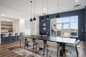 St. Louis Park apartment for rent - a dining room with a black table and chairs and a kitchen with a large window at Verge Apartments in St. Louis Park, MN