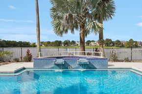 Orlando apartment for rent - A pool surrounded by palm trees and a fence.