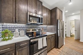 Plano apartment for rent - A kitchen with dark wood cabinets and stainless steel appliances.