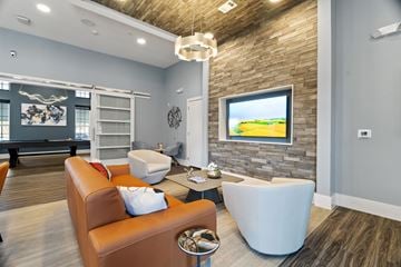 Tomball apartment for rent - A living room with a brown leather couch and a white ottoman.