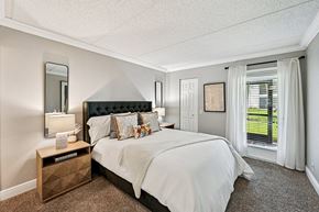Wellington apartment for rent - A bedroom with a large bed and a window with white curtains.