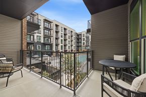 Ft Worth apartment for rent - A balcony with a table and chairs overlooks a pool.