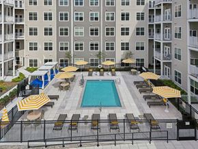 Waltham apartment for rent - A pool surrounded by a black fence and yellow umbrellas.