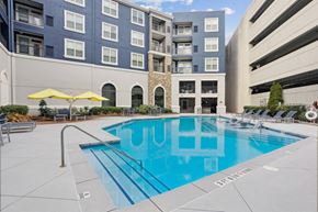 Sandy Springs apartment for rent - A swimming pool in front of a building with a yellow umbrella.