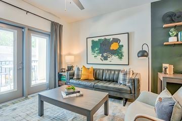 Greensboro apartment for rent - A living room with a grey sofa, a coffee table, and a painting on the wall.