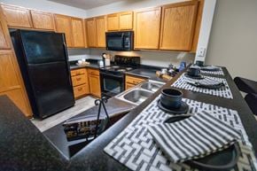 Wilson apartment for rent - A black refrigerator is in a kitchen with wooden cabinets.