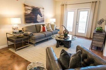 High Point apartment for rent - A living room with a grey couch, a black leather armchair, and a coffee table with a vase on it.