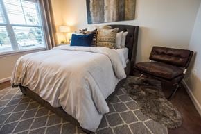High Point apartment for rent - A bedroom with a large bed and a brown leather chair.