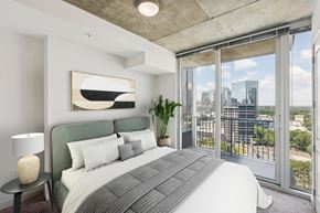 Atlanta apartment for rent - A bedroom with a large bed and a view of the city.