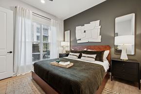 Ft Worth apartment for rent - A bedroom with a large bed and a mirror on the wall.