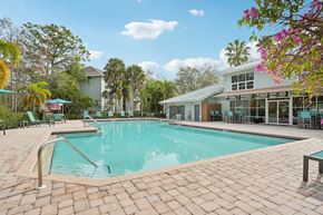 Naples apartment for rent - A large outdoor swimming pool surrounded by a brick patio and lounge chairs.