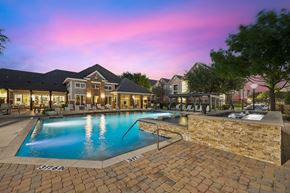 Fort Worth apartment for rent - A swimming pool surrounded by a brick patio and a stone wall.