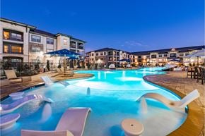 Fort Worth apartment for rent - a large swimming pool with chairs and umbrellas at night