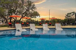 San Antonio apartment for rent - a swimming pool with chairs and umbrellas at sunset