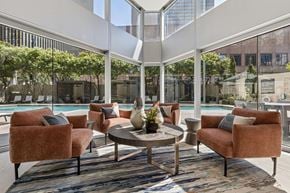 Dallas apartment for rent - A patio with a table and chairs with a view of a pool and trees.