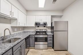 Indianapolis apartment for rent - Indianapolis, IN, Apartments Near Washington Township School District - The Jameson - Kitchen With Custom Gray-and-White Cabinets, Granite Countertops, Ceiling Light, and Stainless Steel Appliances.
