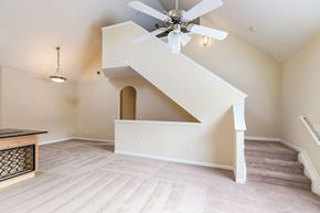 Gainesville apartment for rent - Park Lane Apartments Gainesville, Florida living area with carpeted floors, vaulted ceiling with ceiling fan and light kit, staircase up to the second level