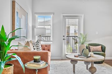 Taylors apartment for rent - A living room with a brown sofa, a green armchair, a wooden coffee table, and a large painting on the wall.