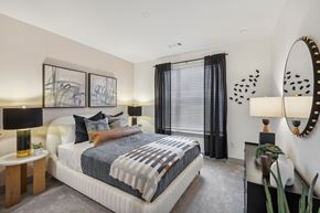 Dallas apartment for rent - A bedroom with a large bed and a mirror on the wall.