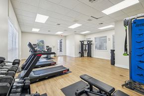Delray Beach apartment for rent - A gym with a variety of equipment including treadmills, weights, and a bench.