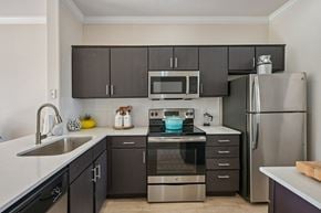 Phoenix apartment for rent - A modern kitchen with dark brown cabinets and stainless steel appliances.