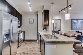 Plano apartment for rent - luxury kitchen with granite countertops, stainless steel appliances, and dark wood cabinetry