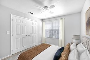 Fort Worth apartment for rent - A bedroom with a bed, a ceiling fan, and a window with curtains.