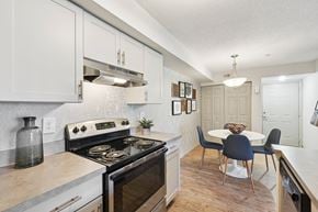 Brandon apartment for rent - A kitchen with a stove top oven and a dining table with chairs.