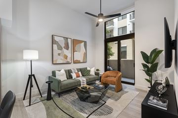 Miami apartment for rent - A living room with a green couch, a black coffee table, and a painting on the wall.