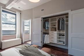Albany apartment for rent - A bedroom with a large bed and a wardrobe with clothes hanging in it.