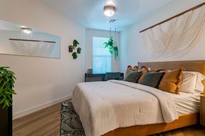Chelmsford apartment for rent - A bedroom with a large bed and a hanging plant.