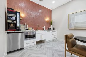 Hollywood apartment for rent - A modern kitchen with a stainless steel refrigerator and oven, white cabinets, and a herringbone patterned floor.