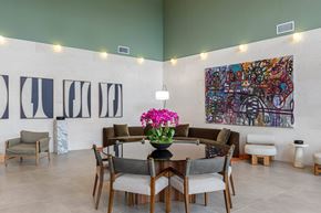 Miami apartment for rent - A dining room with a large painting on the wall and a table set with chairs and flowers.